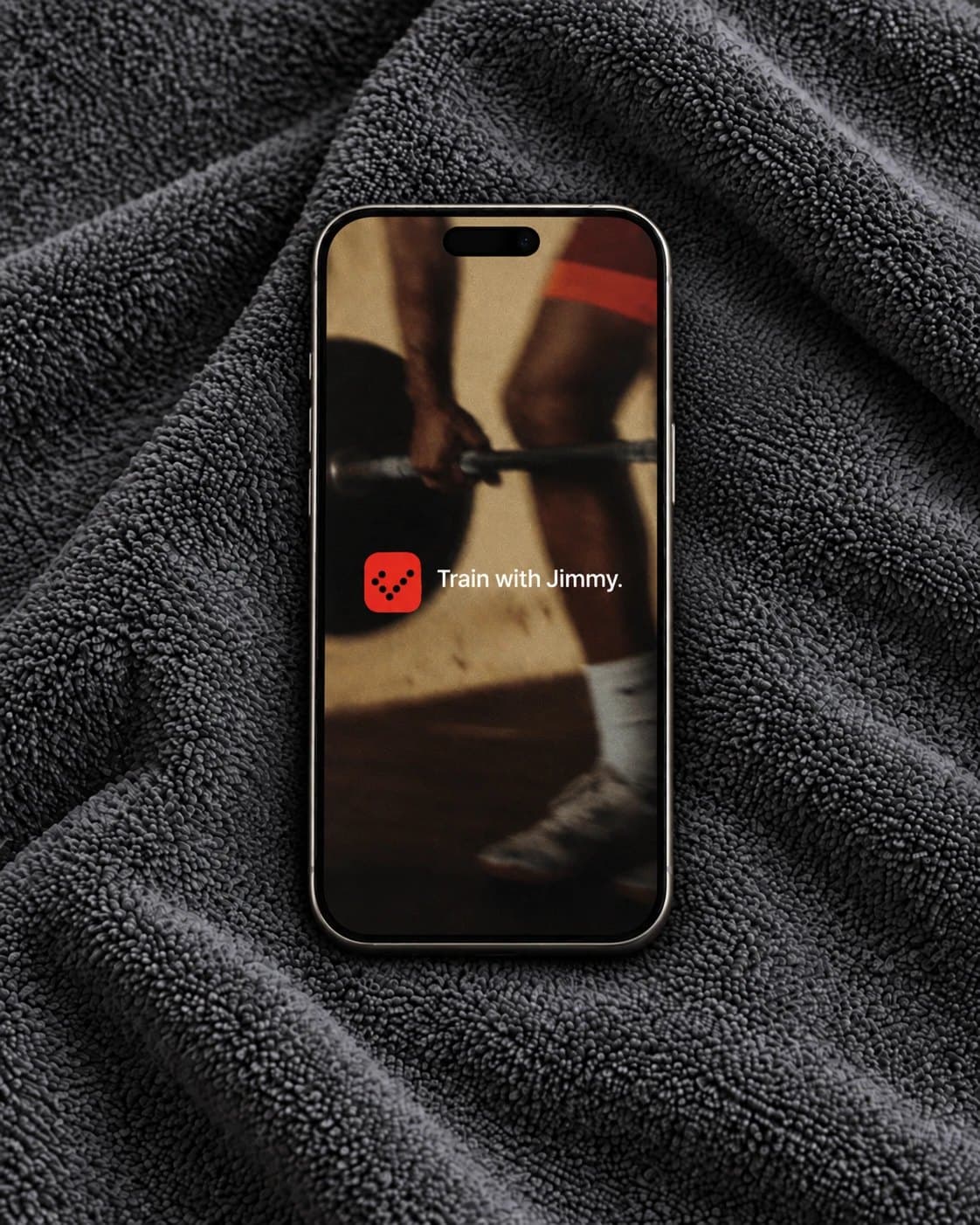 Jimmy on a phone resting on a dark gym towel